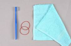 Photograph of a toothbrush, two pieces  of rubber band and a towel.
