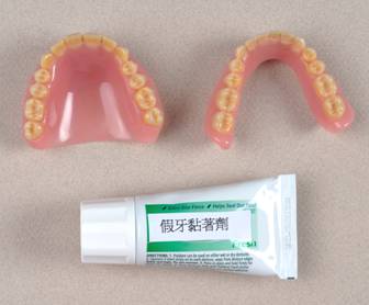 Photograph of a denture and a tube of denture  adhesive.