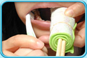 图中所见是让孩子的一边牙齿咬着辅助物件，照顾者则帮孩子刷另一边牙齿。